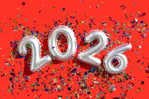 Silver balloons displaying 2026 with confetti on vibrant red background