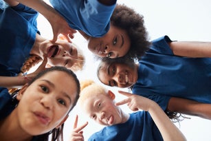 Smiling schoolgirls posing under sky