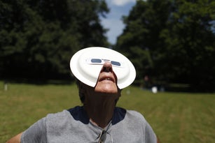 An eclipse watcher uses solar sunglasses taped to a paper plate.
