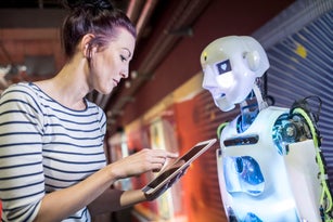 Technician programming human robot through tablet PC at workshop