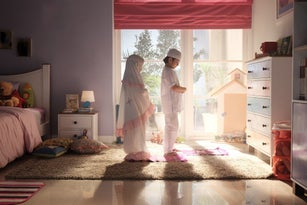 Indonesian Muslim boy teaching his sister to pray during Ramadan