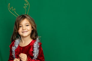 Girl in headband with deer antlers and tinsel smile