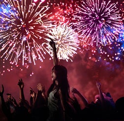 Woman amongst crowd enjoying firework display