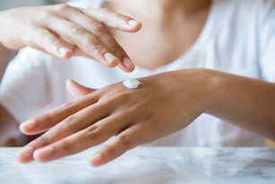 African American woman applying lotion to hand