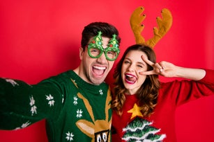 Photo of crazy couple making selfies sticking tongues winking eyes v-signing wear funky ugly ornaments jumpers isolated red color background