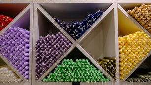 Colorful stick candles arranged on shelves and sorted by color in a candle shop.