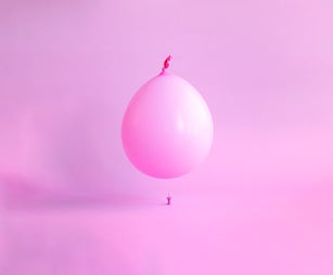 Pink balloon floating over a pink pin