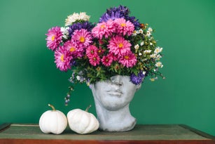Head-shaped vase with a bouquet of flowers.