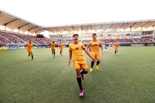 Ecstatic male soccer player runs down a stadium field cheering in celebration during an international match
