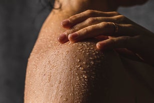 Woman's shoulder with hand on shower