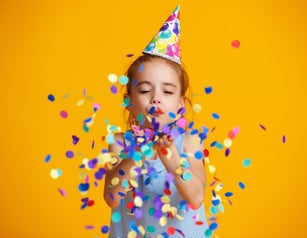 happy birthday child girl with confetti on yellow background