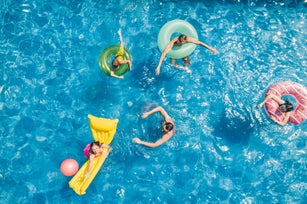 Friends having fun while playing with ball in the swimming pool.  Aerial view.