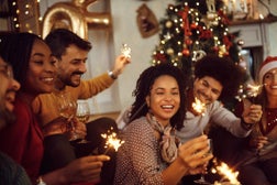 Multiracial group of happy friends using sparklers and having fun on New Year's day at home.