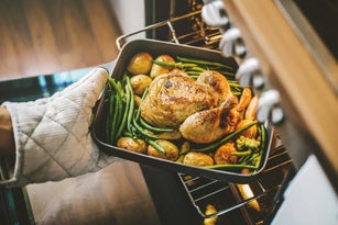 Cook taking ready chicken from the oven