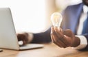 Businessman holding illuminated light bulb, sitting in office