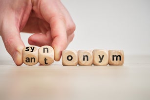 Hand flips wooden cubes with the inscription antonym and synonym