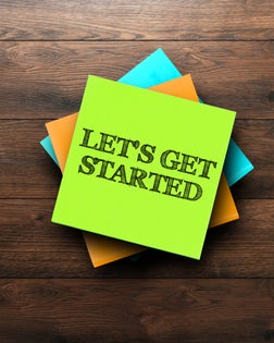 Let's Get Started, the phrase is written on multi-colored stickers, on a brown wooden background. Business concept, strategy, plan, planning.