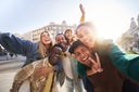 A group of cheerful students college friends taking a selfie as they travel through European cities.