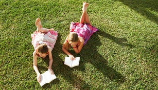 Girls lying on grass reading books