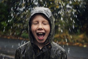 Child standing under water drops outside