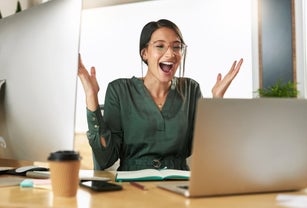 Shot of a young businesswoman cheering during a video conference at work