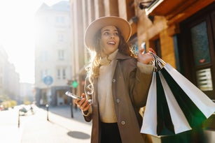 Fall elegant woman carrying shopping bags walking city street.