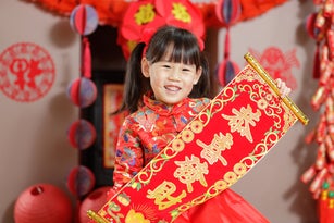 young Chinese girl with traditional dressing up holding "kung hei fat choy" greeting card means "wishing you enlarge your wealth" celebrate Chinese New Year