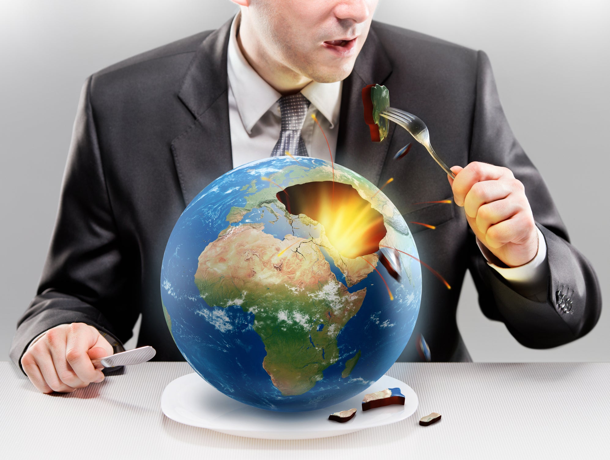 Greedy businessman eating planet Earth