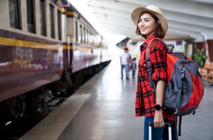 Young asian woman traveler with backpack in the railway, Backpack and hat at the train station with a traveler, Travel concept. Woman traveler tourist walking at train station
