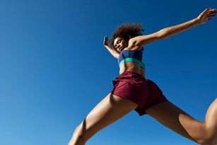 Young woman exercising against clear sky