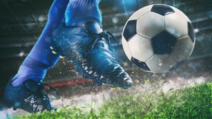 Football scene at night match with close up of a soccer shoe hitting the ball with power