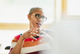 Medium shot businesswoman in discussion with colleague at workstation