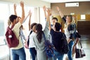 Group of students standing in a circle with hands raised in the air