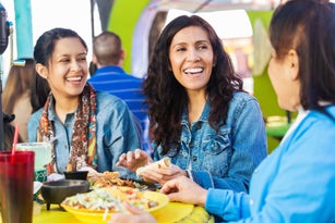 Adult sisters having lunch with mother outdoors at Mexican restaurant