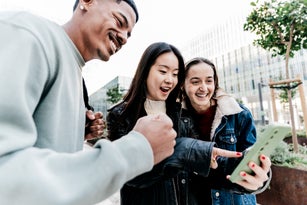 Students celebrating while looking the mobile phone outdoors