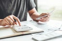 Man using calculator Accounting Calculating Cost Economic bills with money stack step growing growth saving money in home , finance concept
