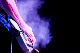 Close-up of side view of a man musician hands playing a chord on an electric guitar during a popular music concert