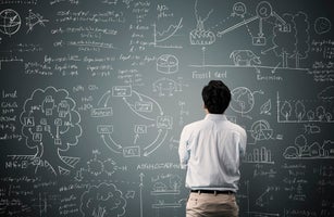 Man looking to formula and picture on blackboard
