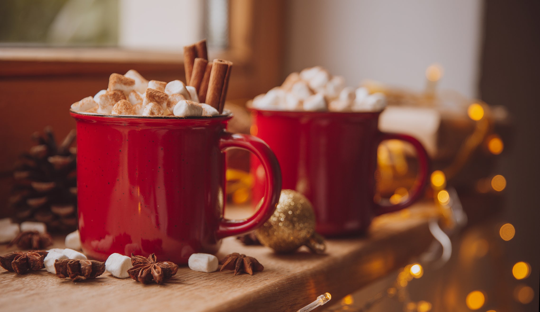 Christmas festive holiday mood composition with coffee in rustic cup, candles and decorative toys on wooden board over white windowsill at background. Christmas greeting card