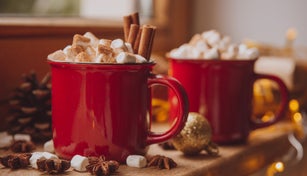Christmas festive holiday mood composition with coffee in rustic cup, candles and decorative toys on wooden board over white windowsill at background. Christmas greeting card