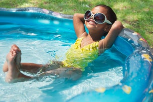 Hispanic girl relaxing in kiddie pool
