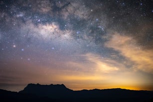 The galaxy containing Earth's solar system is shown above mountains.