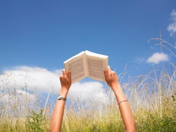 woman reading in field of high grasses
