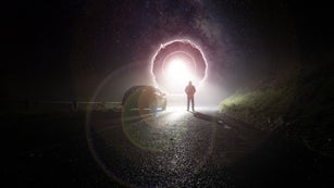 A lone car, parked on the side of the road, underneath a glowing UFO portal, with a hooded figure, on a spooky, scary, rural, country road. On a foggy winters night