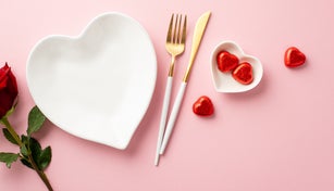 Valentine's Day concept. Top view photo of heart shaped dish cutlery chocolate candies and rose on isolated pastel pink background with copyspace