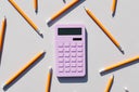 Calculator and non-colored pencils on a gray background. Universal gray background. Calculator. Educational supplies.