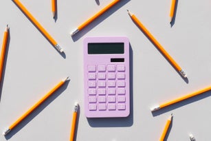 Calculator and non-colored pencils on a gray background. Universal gray background. Calculator. Educational supplies.