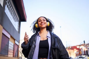 Cheerful woman listening to music with a mobile outdoors