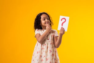 Thoughtful kid girl holding question mark card. Children, idea and knowledge concept