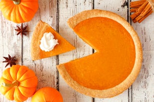 Pumpkin pie with slice removed, top view table scene on white wood